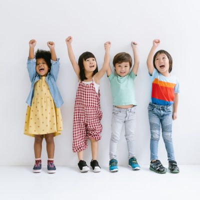Group of Diverse Ethnicity Little kids raising hands up and smiling Isolated on gray background. Childhood, freedom, happiness, active lifestyle concept.